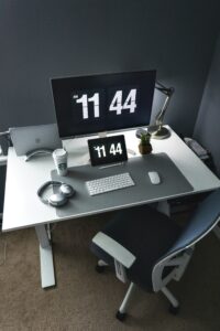 Bureau minimaliste avec écran affichant l’heure, symbole de gestion du temps et de recentrage sur l’essentiel pour les professions libérales