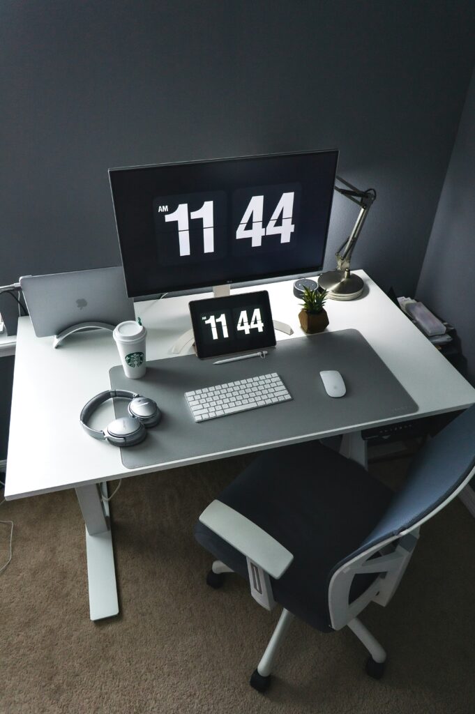 Bureau minimaliste avec écran affichant l’heure, symbole de gestion du temps et de recentrage sur l’essentiel pour les professions libérales