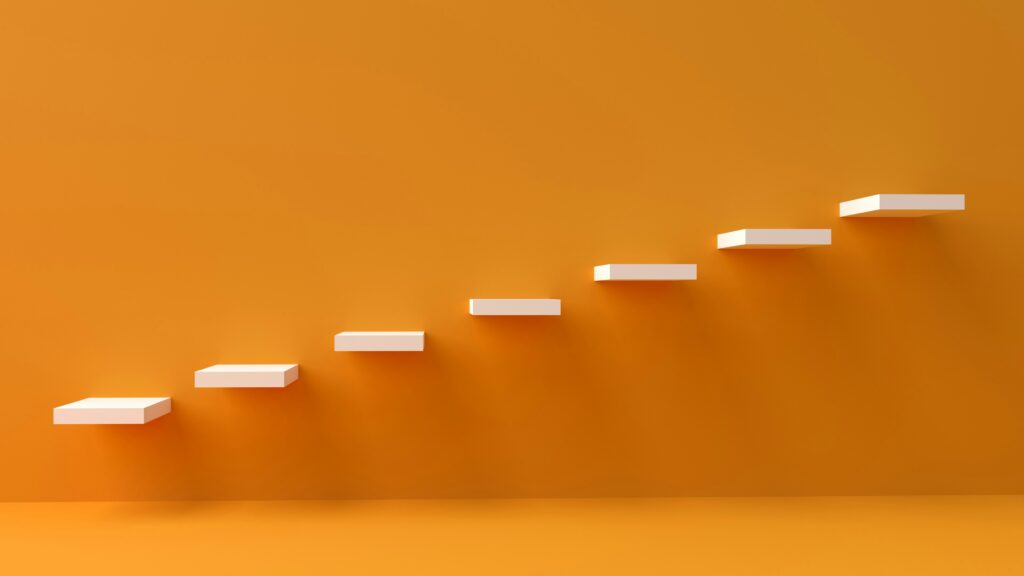 Marches blanches sur fond orange illustrant la progression étape par étape, symbole des petites habitudes qui mènent à de grands résultats.