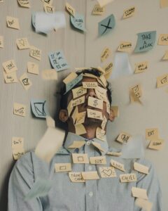 Personne débordée couverte de post-its illustrant une surcharge de tâches professionnelles à déléguer
