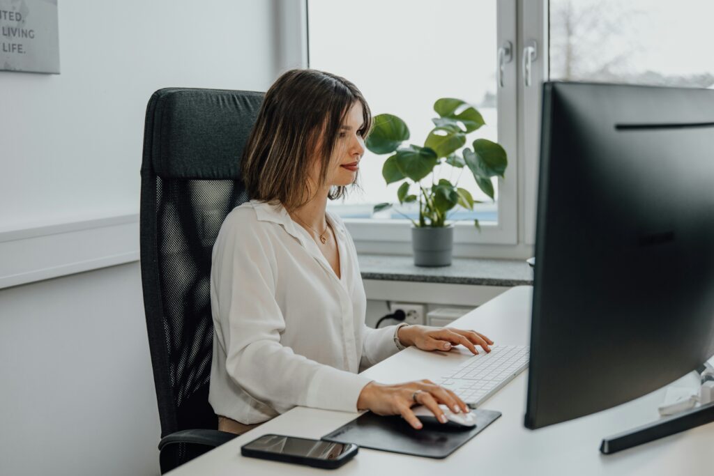 Femme assise devant un ordinateur illustrant les services de secrétariat externalisés par Optim Office